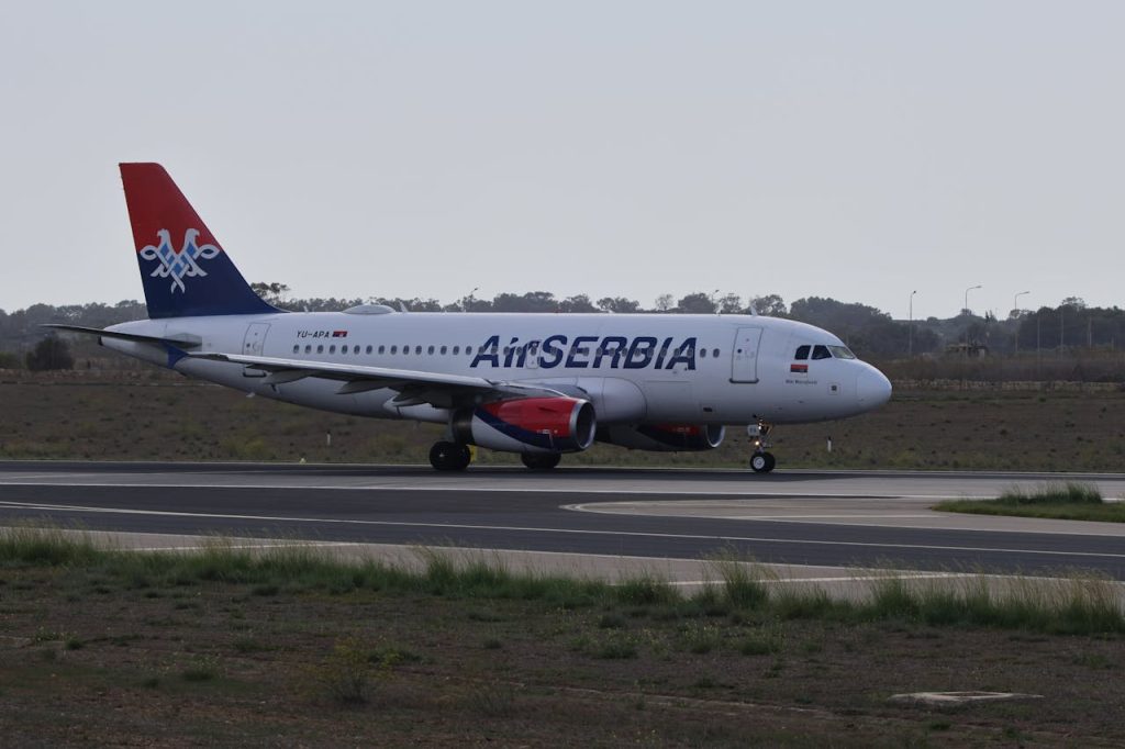 Air Serbia aircraft taxiing on runway, ready for takeoff.